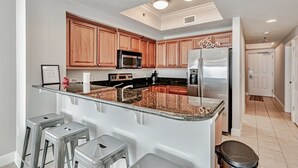 A modern kitchen with wooden cabinets, stainless steel appliances, and a granite countertop.