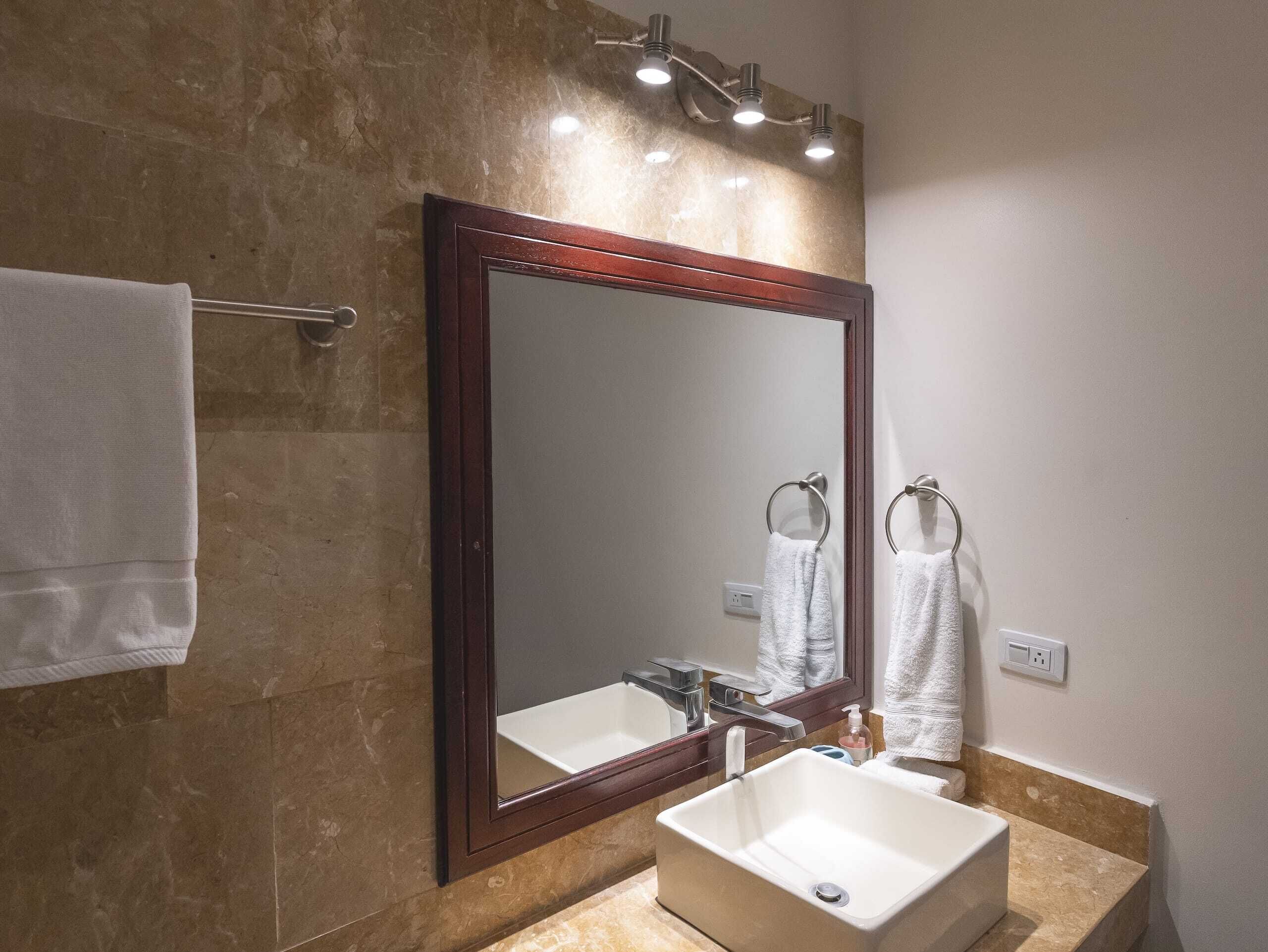 Un baño con un espejo grande, un lavabo y un perchero para toallas.
