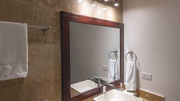 Un baño con un espejo grande, un lavabo y un perchero para toallas.