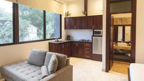 Eine moderne Küche mit dunklen Holzausziehtüren, einem Edelstahlkühlschrank und einem Fenster mit Blick auf Grünflächen.