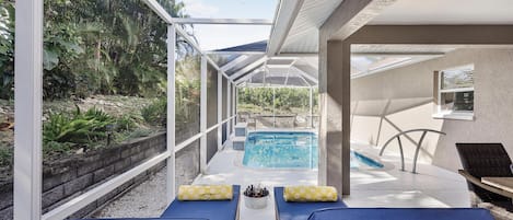 Un área junto a la piscina con sillones de descanso, un jacuzzi y vistas al follaje circundante.