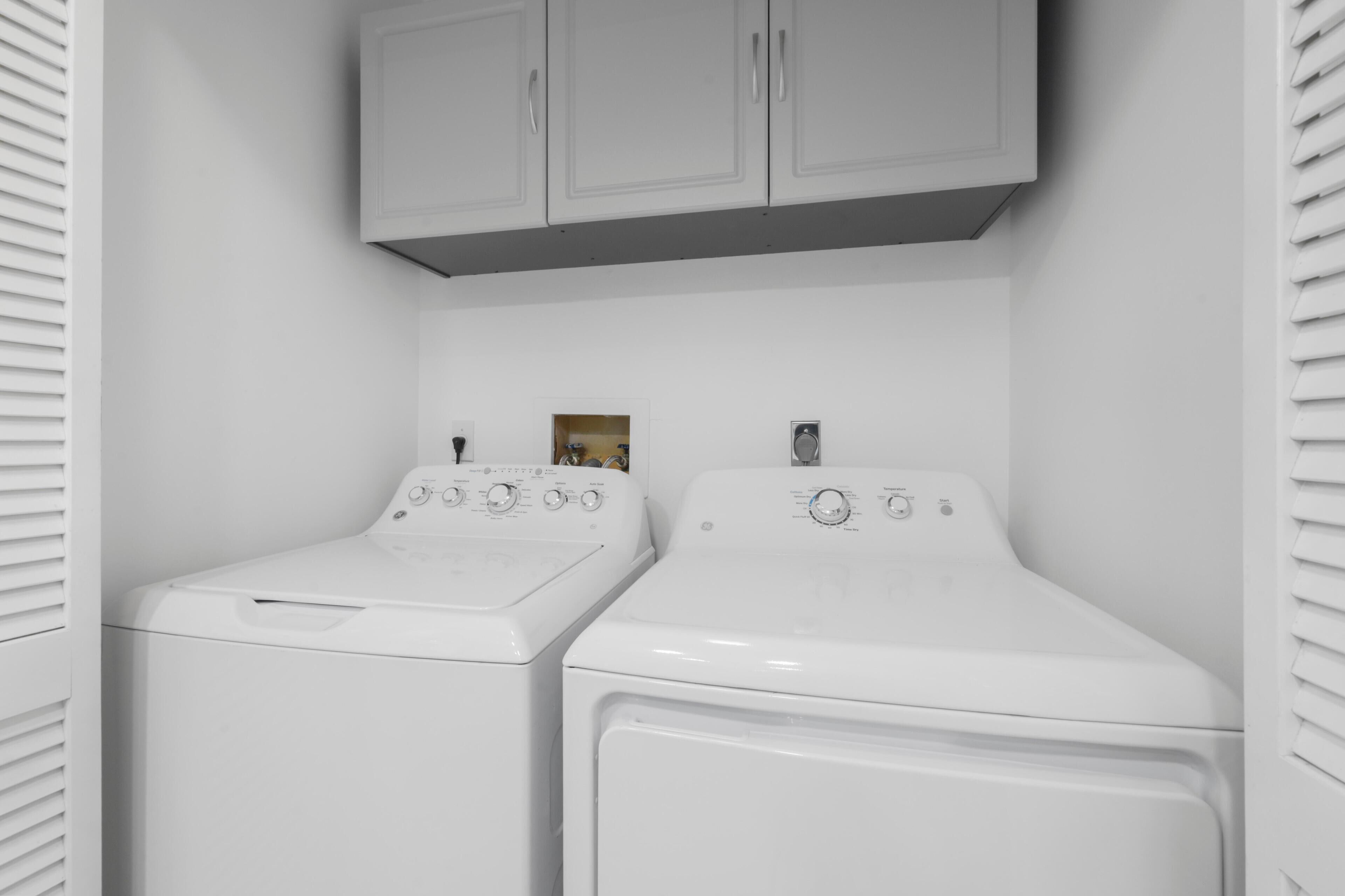 Une buanderie avec deux machines à laver blanches et un meuble de rangement au-dessus.