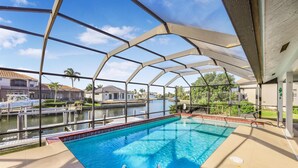 An indoor swimming pool with clear views of a marina and residential buildings. - Quiet Waterfront Home With Pool, Dock and Bicycles (Marco Island)