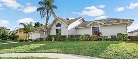 A modern two-story house with a well-maintained lawn, a driveway, and a palm tree.