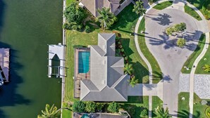 An aerial view of a residential area with a swimming pool, a dock, and a circular driveway. - Quiet Waterfront Home With Pool, Dock and Bicycles (Marco Island)