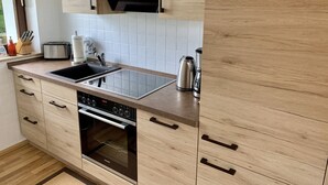 Et moderne køkken med træskabe, en stålvask, en indbygget ovn og en brødrister.