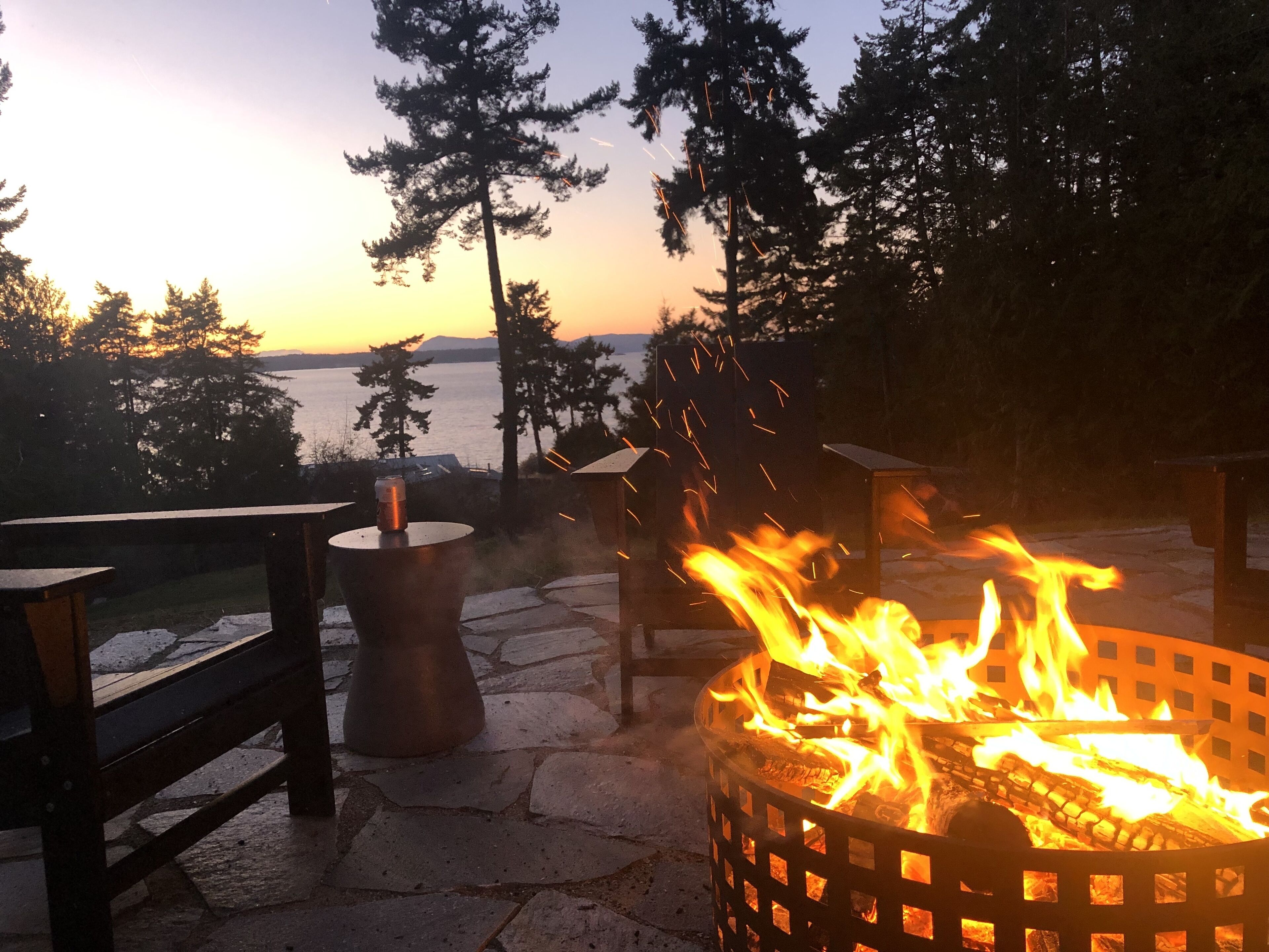 A fire pit with flames, surrounded by stone steps and a metal table.