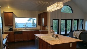 Una cocina moderna con armarios de madera, una isla grande con lavamanos y vistas al exterior.