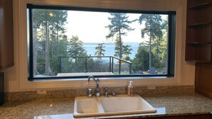 Una cocina con un ventanal que ofrece vistas a una terraza y un bosque.