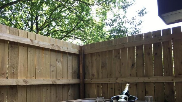 A hot tub with a bottle of champagne and two glasses, surrounded by wooden fencing. - Shrew Lodge Hot Tub (Carmarthen)