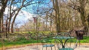 A park with a metal table and chairs, surrounded by a fence and trees. - Woodlands - Bridlington Links (Sewerby, near Bridlington)