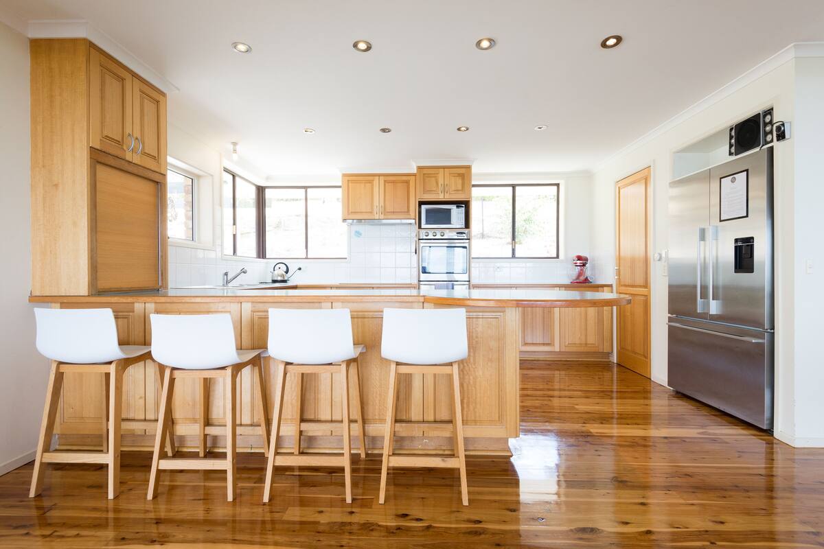 Une cuisine moderne avec des meubles en bois, des appareils électroménagers en acier inoxydable et un îlot central doté de tabourets de bar.