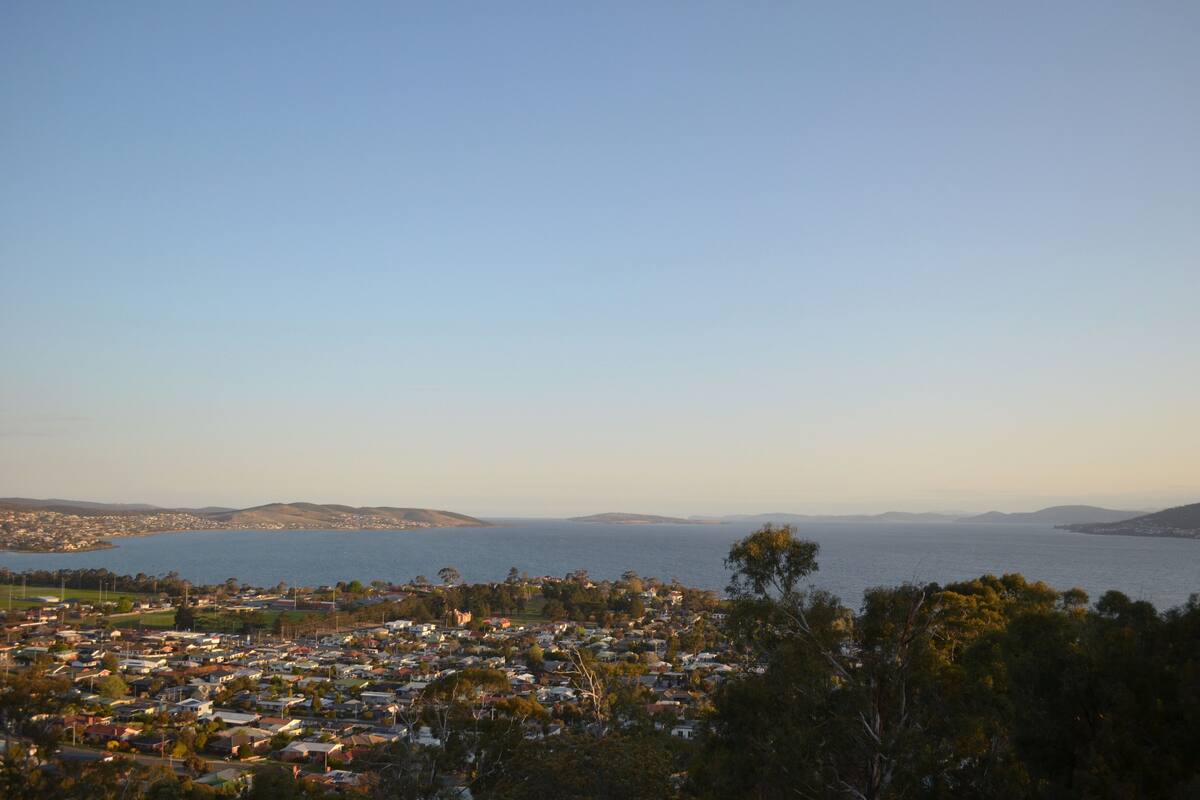 Une ville côtière offrant une vue sur la mer et les collines lointaines.
