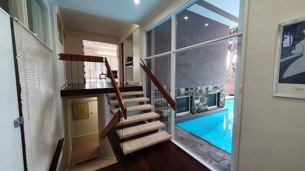 Escadaria que leva a um segundo andar com vista para uma piscina.