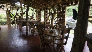 A rustic wooden dining area with tables and chairs, surrounded by wooden beams and branches. - Oski Lodge  (Guayabo)