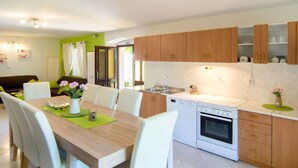 Eine moderne Küche mit Holzschränken, einem weißen Herd und einem Essbereich mit Holztisch und Stühlen.