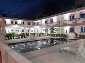 A multi-story hotel with a central courtyard featuring a swimming pool, outdoor seating, and potted plants. - Hotel Real Da Vinci Acapulco (Acapulco)