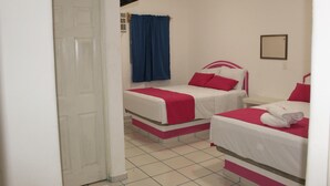 A hotel room with two beds, each with a red and white bedspread, a blue curtain, and a flat-screen TV mounted on the wall. - Hotel Real Da Vinci Acapulco (Acapulco)