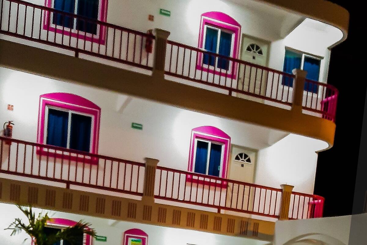 A multi-story building with balconies, a pool, and a sign indicating "RECEPTION".