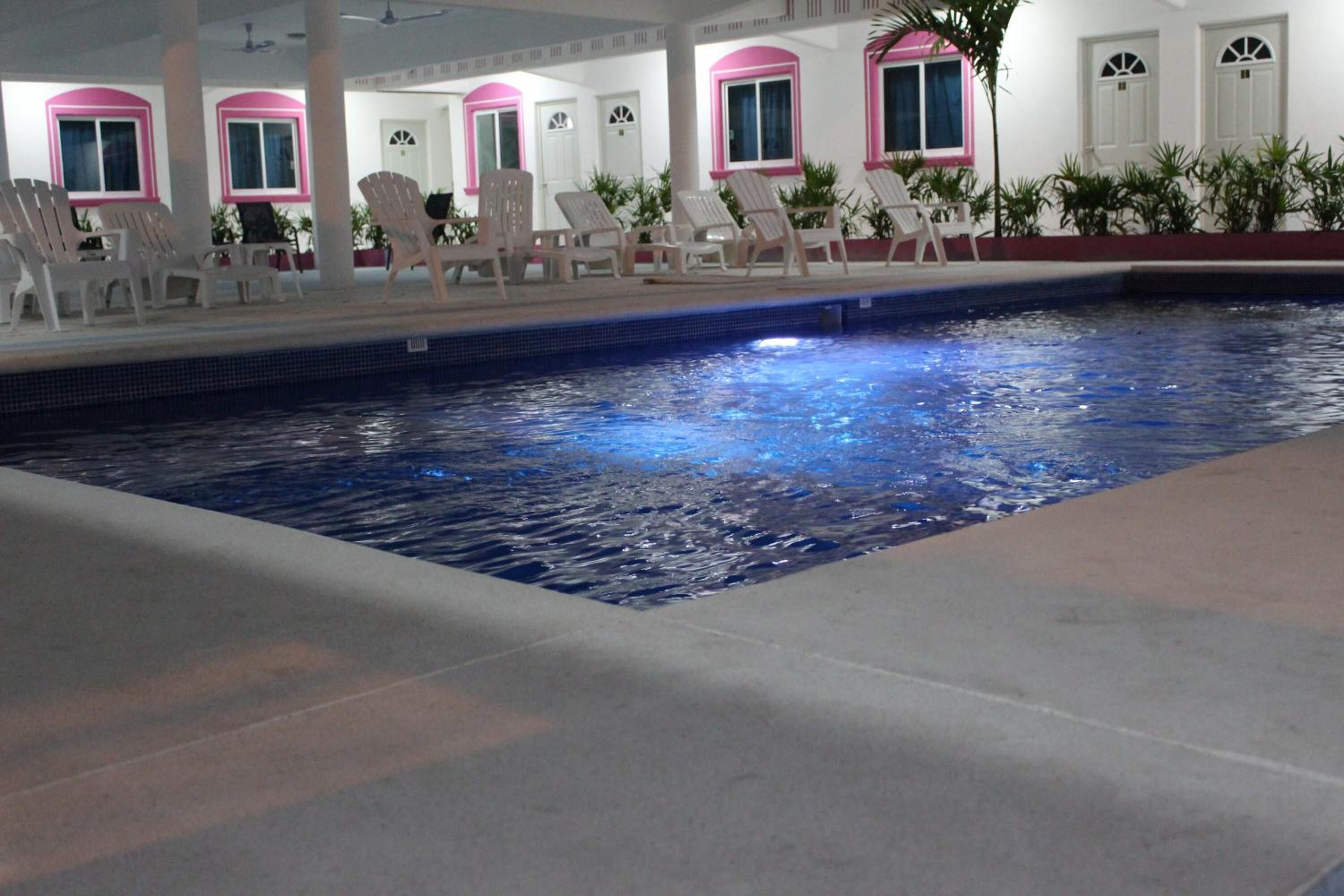 An indoor swimming pool with lounge chairs and a tiled floor.
