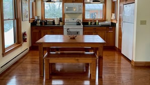 Une cuisine avec des meubles en bois, une cuisinière blanche, un four à micro-ondes et des luminaires suspendus.