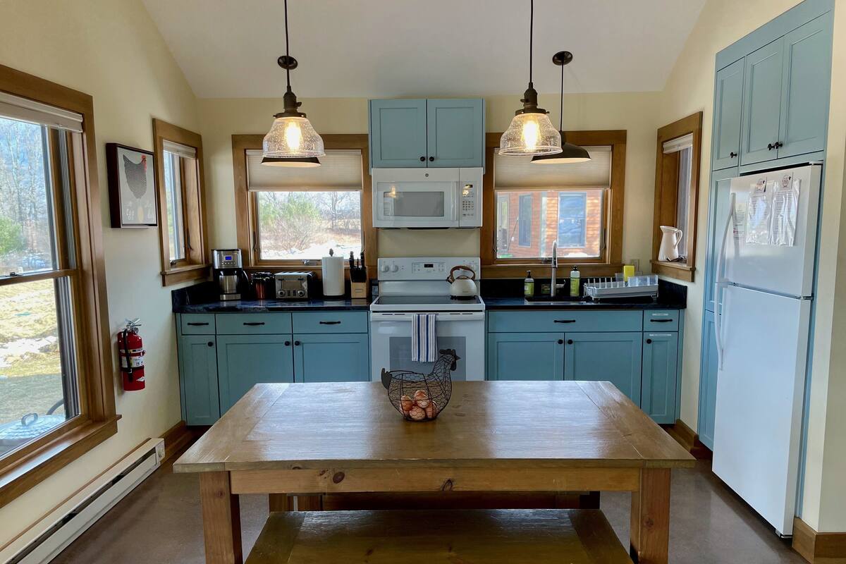 A kitchen with light blue cabinets, a wooden table, and two pendant lights.