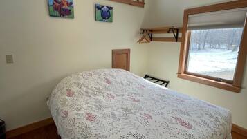 A bedroom with a large bed, two windows, and a door.