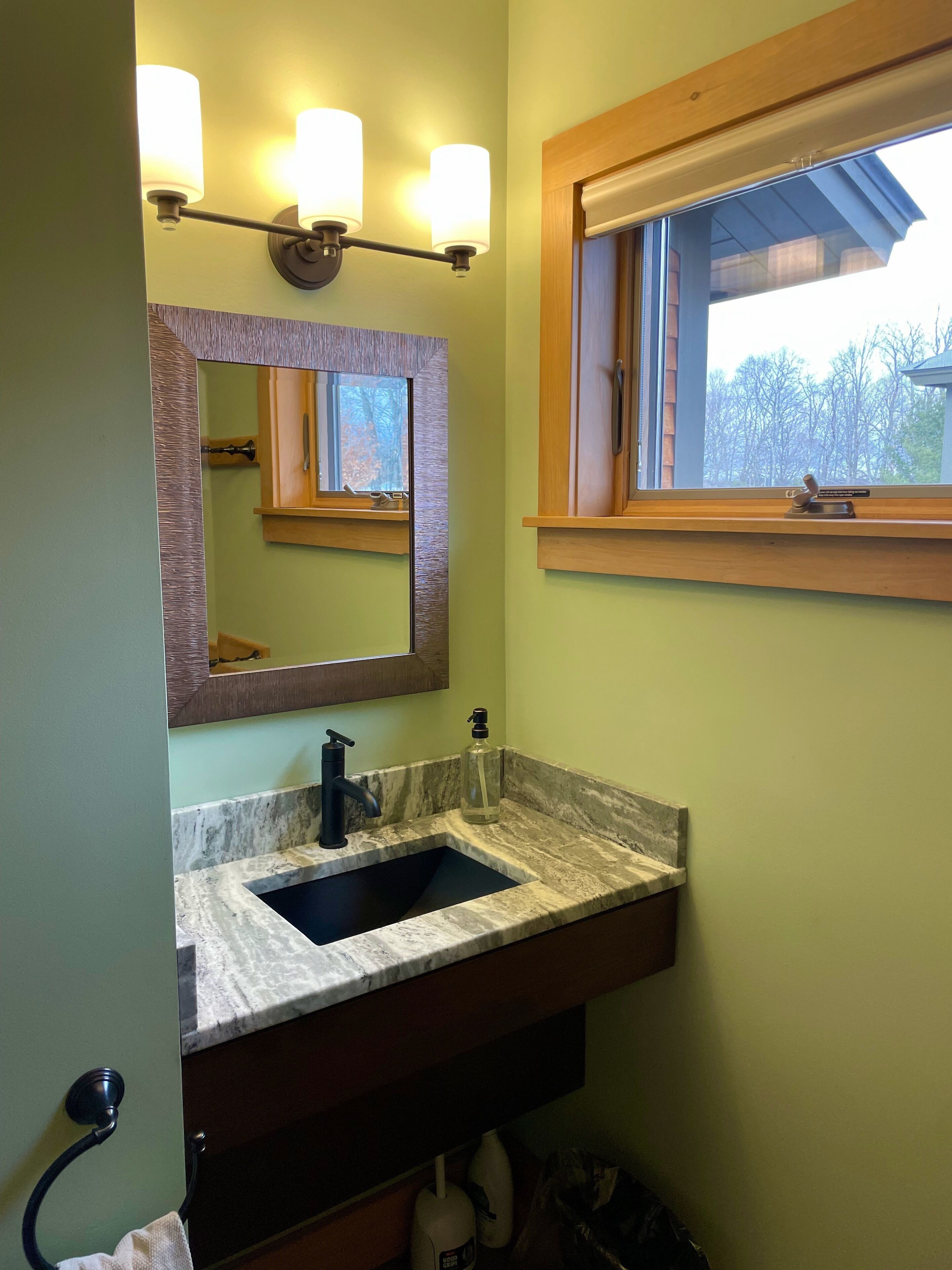 Un bagno con un lavabo in marmo, uno specchio, una finestra e un porta asciugamani.