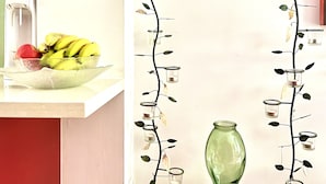 Un comptoir de cuisine avec un panier de fruits, un élément décoratif mural et un vase.