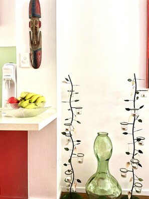 Una encimera de cocina con un frutero, un adorno de pared y un florero.