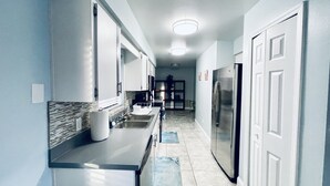 Una cocina moderna con armarios blancos, un refrigerador de acero inoxidable y suelo de baldosas.