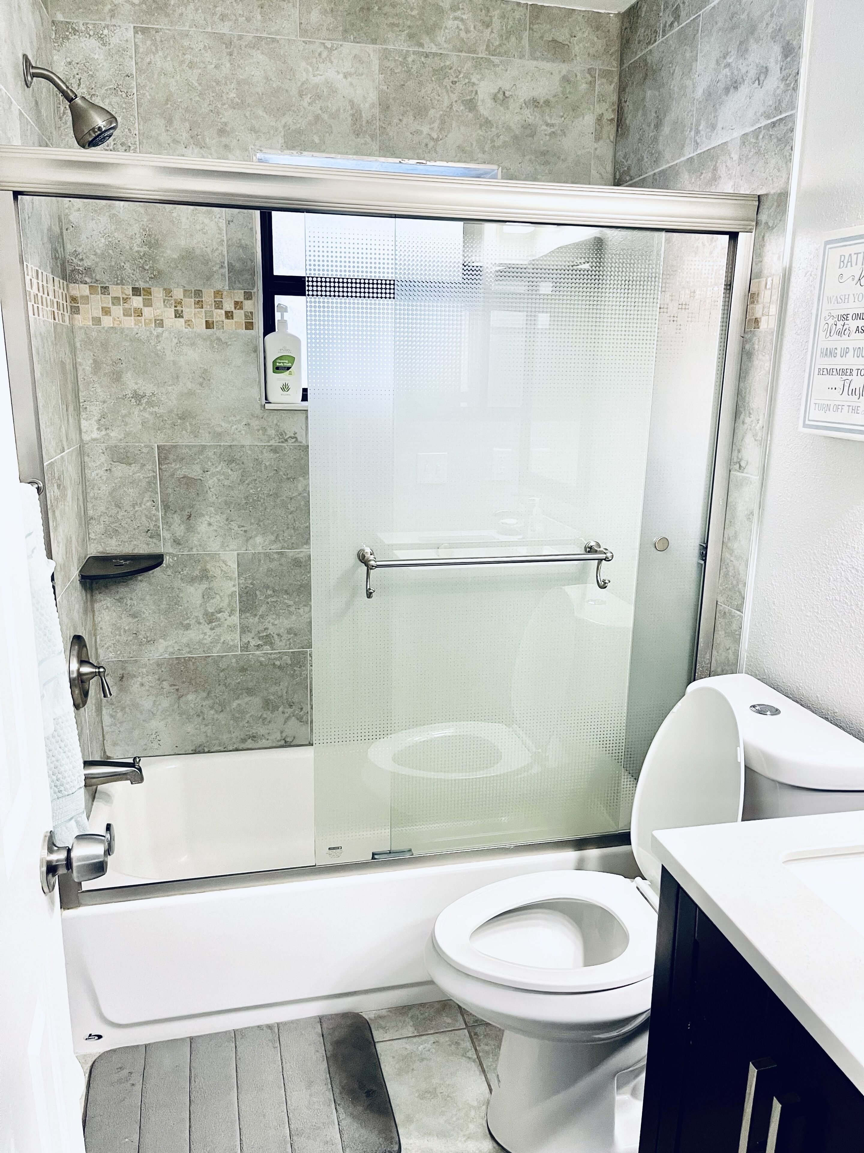 A modern bathroom with a glass-enclosed shower, a white toilet, and a bathtub.