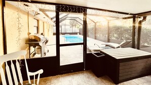 Una habitación iluminada por el sol con vista a una piscina, una parrilla y una zona de estar.