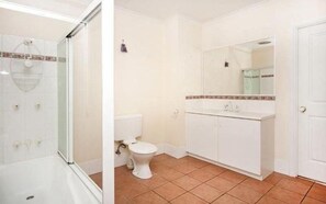 A bathroom with a shower, toilet, and sink. - Cairns City Garden Apartment (Parramatta Park)