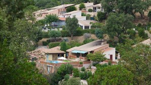 Zona residencial con casas rodeadas de vegetación, una piscina y un pequeño patio.