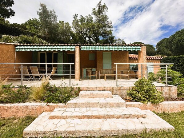 A rustic building with a tiled roof, a covered patio with outdoor seating, and a stone staircase leading to the entrance.