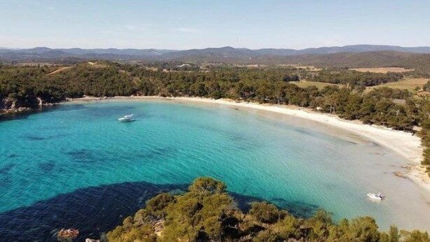 Un paisaje costero con un mar turquesa cristalino, una playa arenosa y un bote.