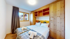 Un dormitorio con dos camas, cabeceros de madera, una ventana con cortinas y vistas a edificios.