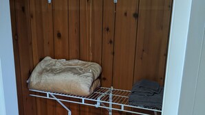 Una habitación pequeña y cerrada con paredes de madera y un estante metálico.