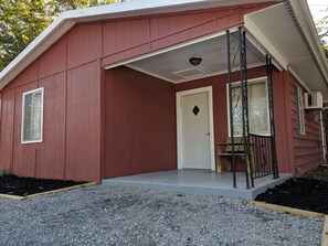 A red single-story building with a covered porch, a door, and a window. - Clean, full kitchen, stand alone cabin (Cadiz)