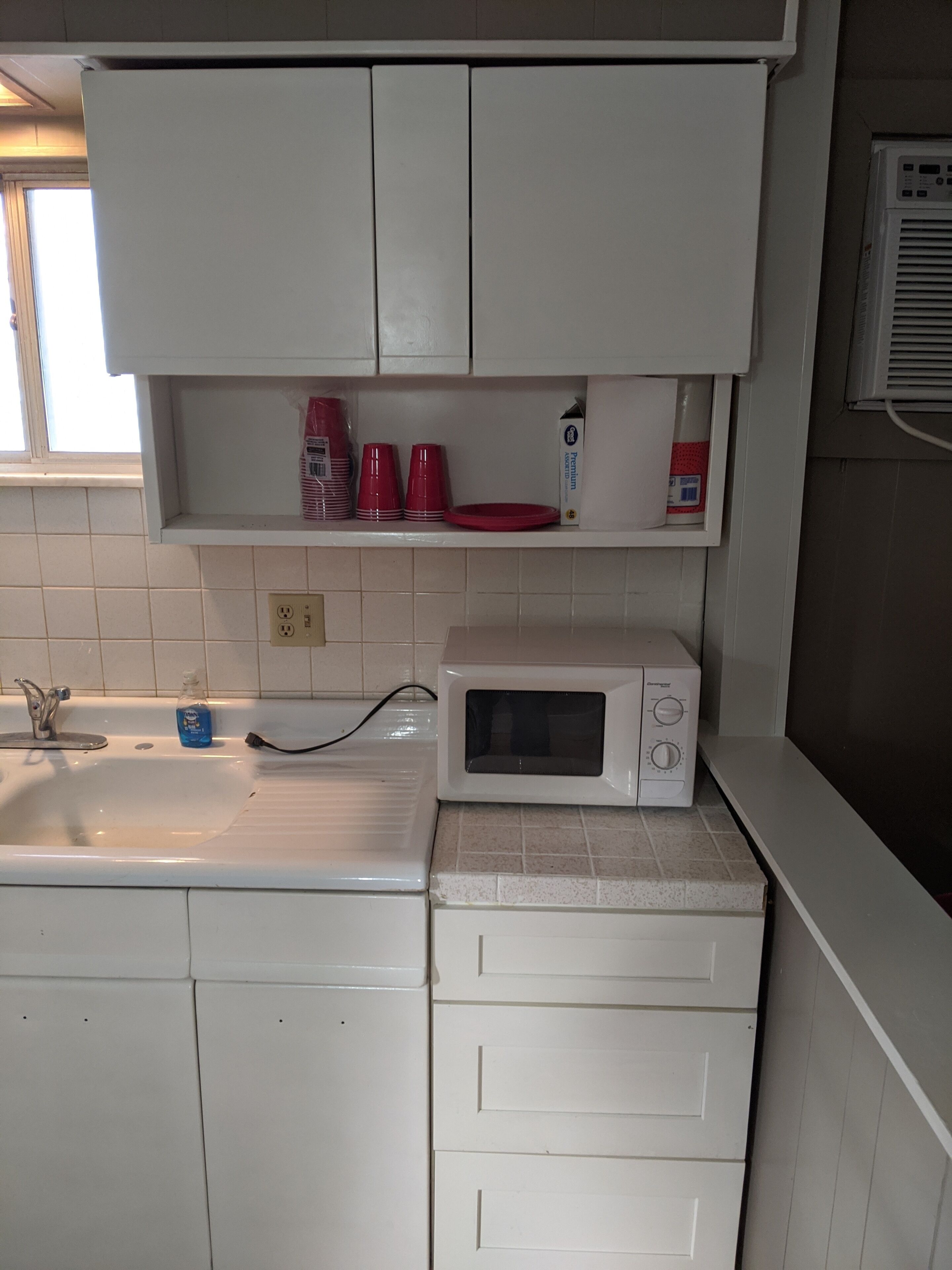 A compact kitchen with white cabinets, a microwave, and a sink.