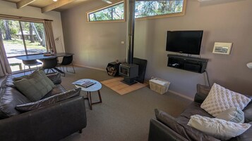 Una sala de estar acogedora con chimenea, sofás de cuero, televisor y comedor con mesa y sillas.