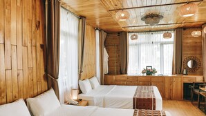 A hotel room with wooden walls and ceiling, two beds with white linens, a wooden desk, and a mirror. - Tam Coc Dibi Villa (Nam Hoa Lu)