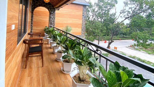 A balcony with wooden flooring, potted plants, and a view of the street. - Tam Coc Dibi Villa (Nam Hoa Lu)
