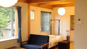 A cozy room with a wooden ceiling, a sofa, a table, and a bed.