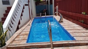En rektangulär swimmingpool med en kant av kakel, omgiven av en kakelbeklädd yta.