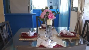 En matplats med ett glasbord, stolar med blommigt tyg och en vas med rosa blommor.