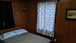 A wooden room with a bed, a patterned curtain, and a wall-mounted owl decoration. - Stand alone cabin,  sanitized, full kitchen. (Cadiz)