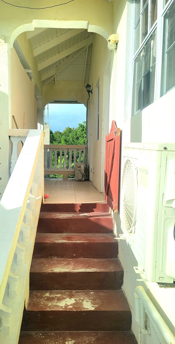 Una escalera que conduce a un balcón con vistas a la vegetación.