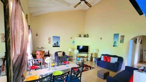 A spacious living room with a dining area, a sofa, a TV, and a ceiling fan.